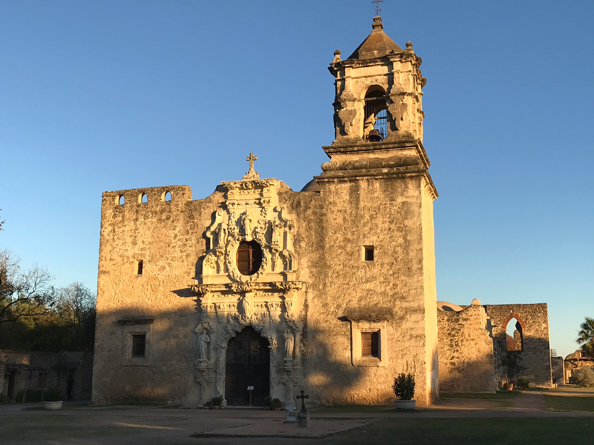 Mission San José in San Antonio, Texas, illuminated by warm late-afternoon light beneath a clear blue sky.