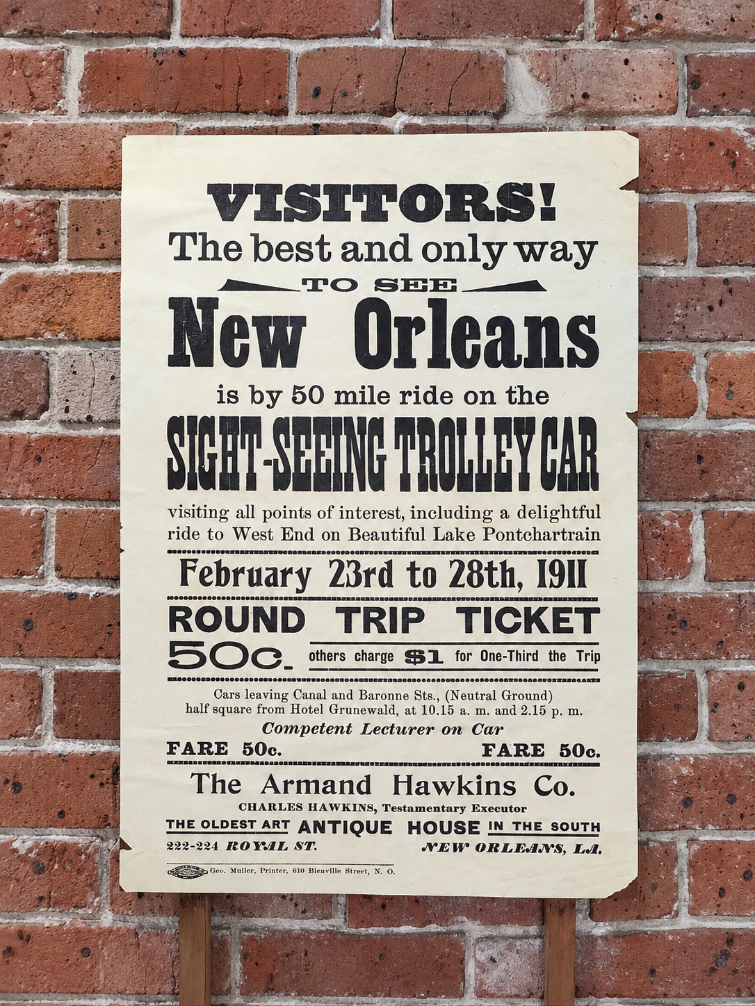 A weathered 1911 New Orleans sightseeing trolley advertisement mounted on a brick wall.